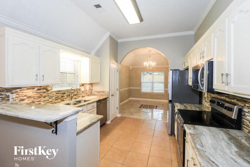 a large kitchen with marble counter tops and white cabinets