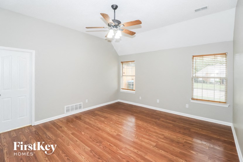 an empty living room with wood flooring and a ceiling fan