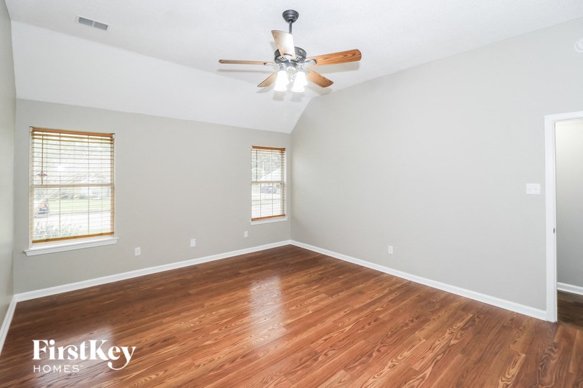 an empty living room with wood flooring and a ceiling fan