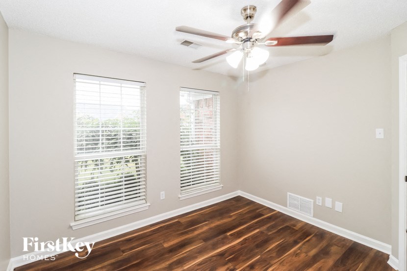 an empty living room with a ceiling fan and two windows