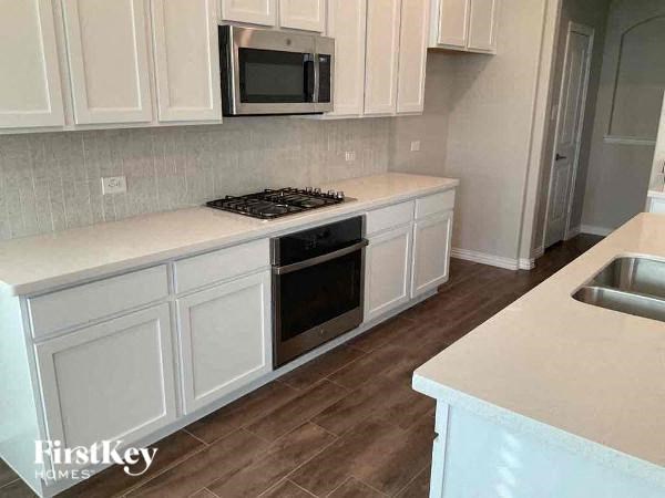 a kitchen with white cabinets and a stove and a microwave