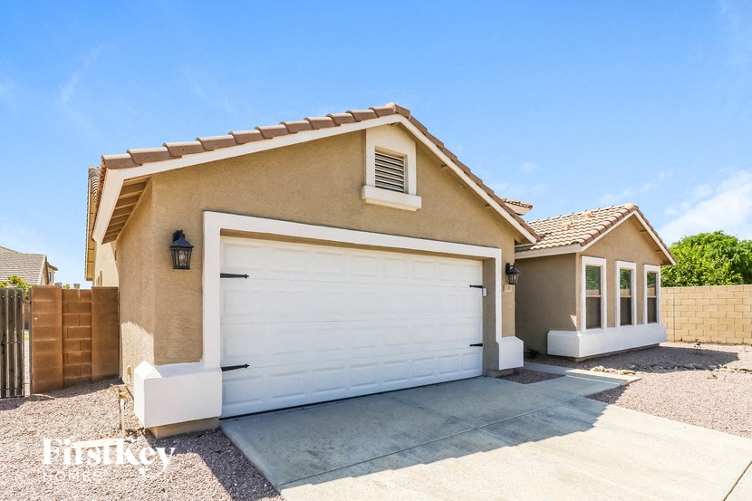 A beige house with a white garage door and a brown fence.