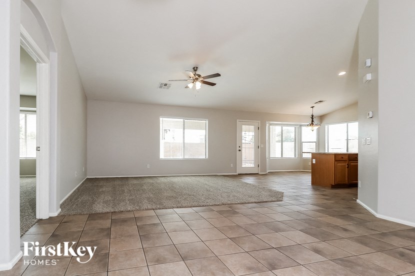 A spacious living room with a rug, a ceiling fan, and a cabinet.