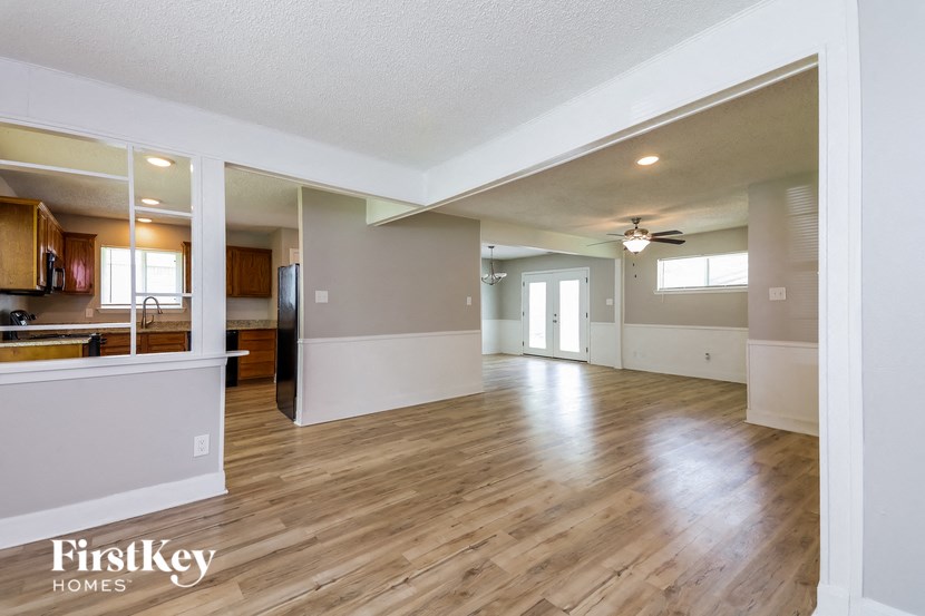 an empty living room and kitchen with wood flooring