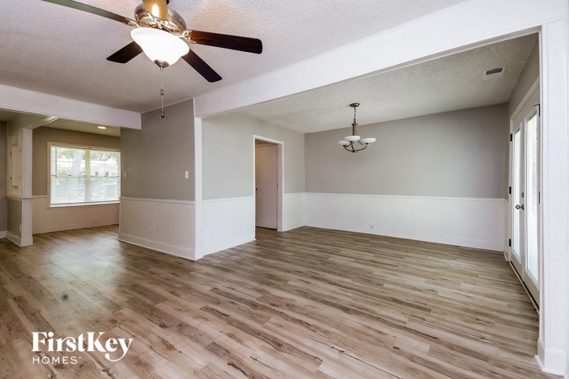 the living room and dining room with wood flooring and a ceiling fan