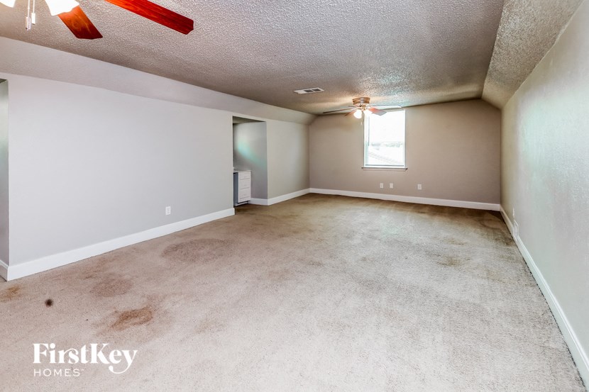 an empty living room with a ceiling fan and a window