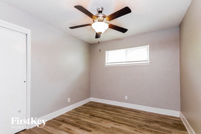 an empty room with a ceiling fan and a window