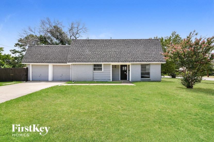 a small white house with a grassy yard and a driveway