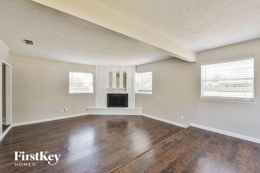 an empty living room with wood floors and a fireplace