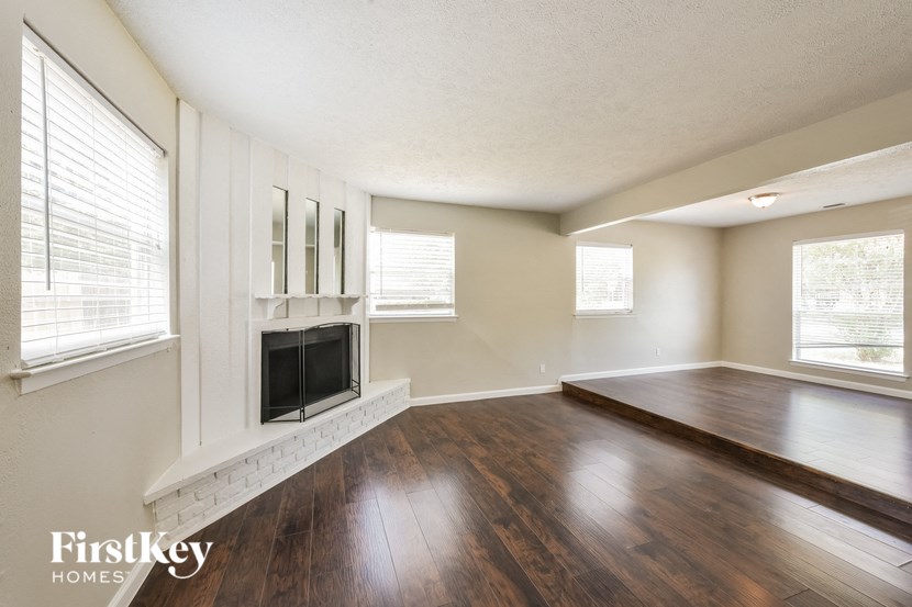 an empty living room with a fireplace and wooden floors