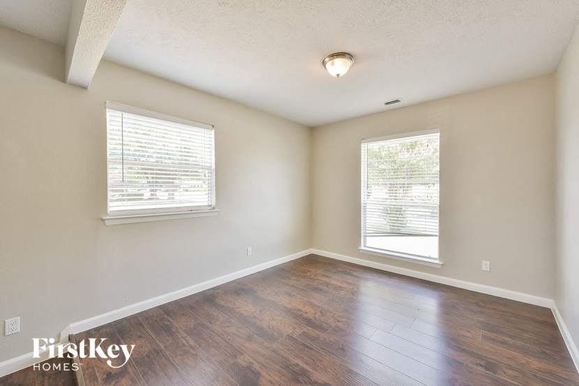 an empty living room with wood flooring and two windows
