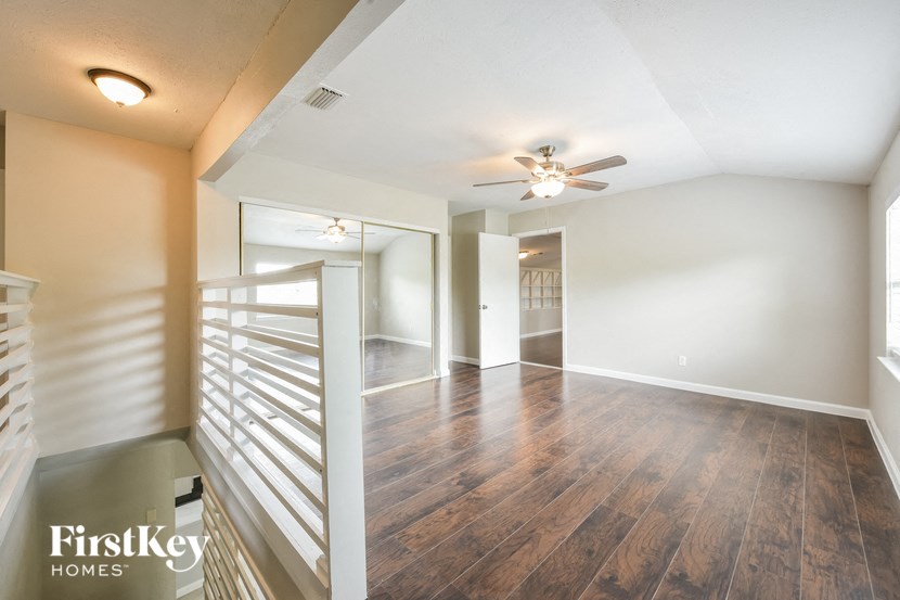 an empty living room with a ceiling fan and a staircase