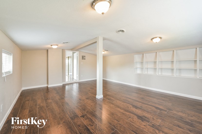 an empty living room with a wood floor and white shelves