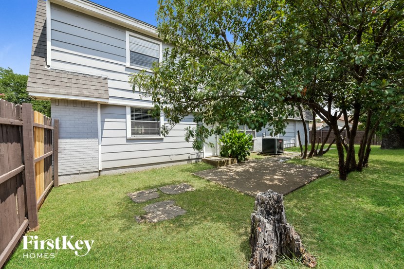 a backyard with a tree and a white house