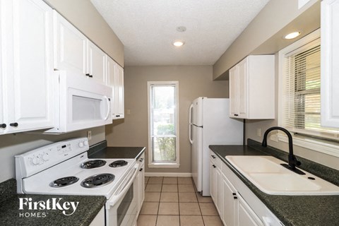 a kitchen with white cabinets and a sink and a stove