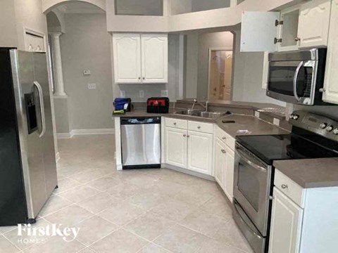 A kitchen with a black refrigerator and white cabinets.