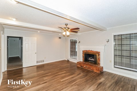A spacious living room with a fireplace and a ceiling fan.