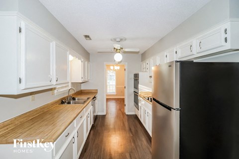 A kitchen with wooden countertops and white cabinets.