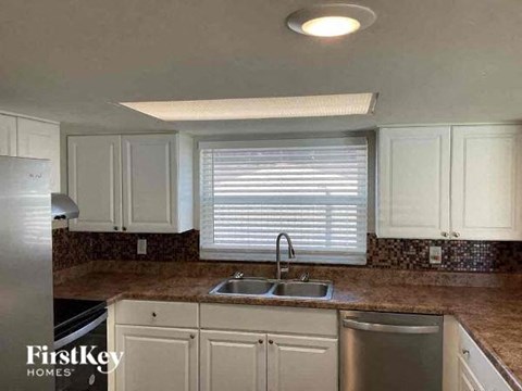 A kitchen with white cabinets and a granite countertop.