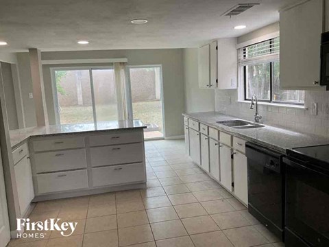 a kitchen with white cabinets and a sink and a window