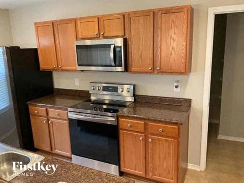 A kitchen with wooden cabinets and a black refrigerator.