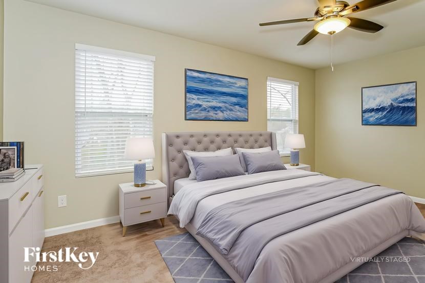 A bedroom with a bed, nightstands, and pictures on the wall.