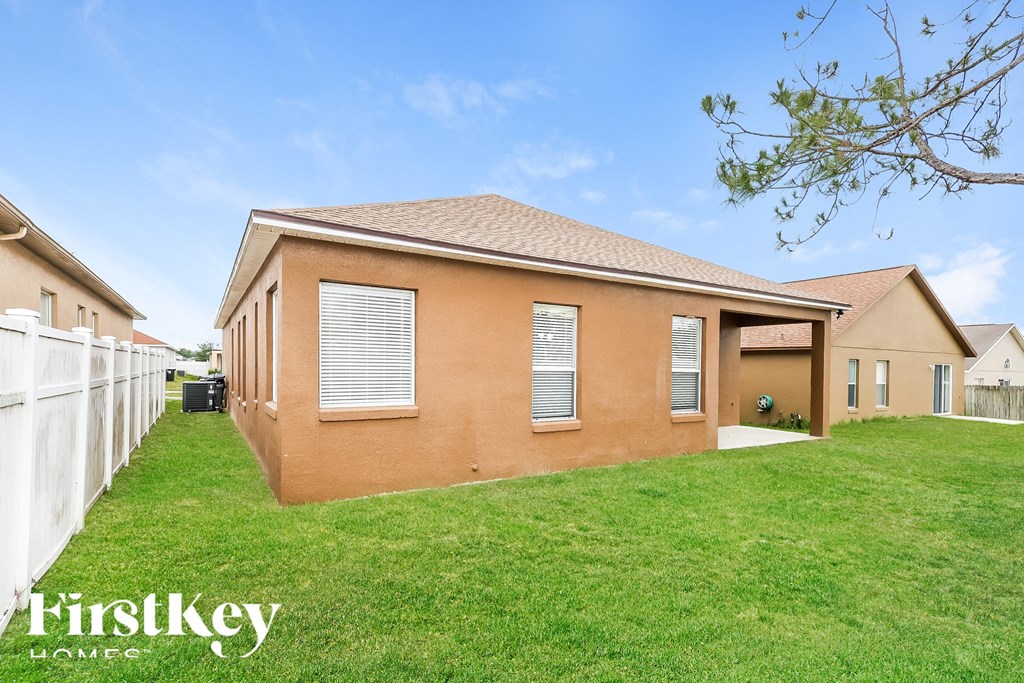 A brown house with a white fence and green grass in front.
