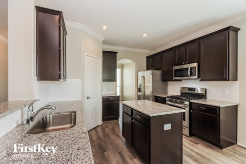 A kitchen with dark brown cabinets and a granite countertop.