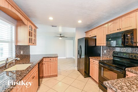 a kitchen with wood cabinets and black appliances and granite counter tops