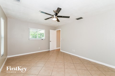 the living room has a ceiling fan and a tiled floor