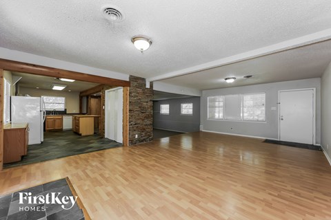 A spacious living room with wooden floors and a stone pillar.