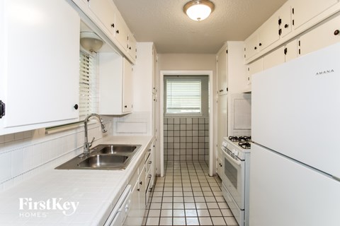 A white kitchen with a sink and a stove top oven.