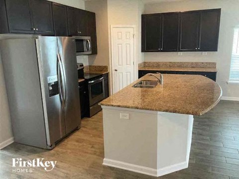 A kitchen with a granite countertop and a stainless steel refrigerator.