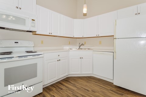 A kitchen with white cabinets and a stove top oven.