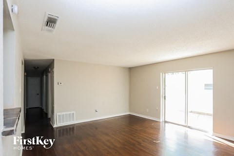 A room with wooden floors and a sliding glass door leading to a balcony.