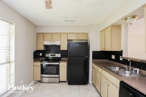 A kitchen with black appliances and beige cabinets.