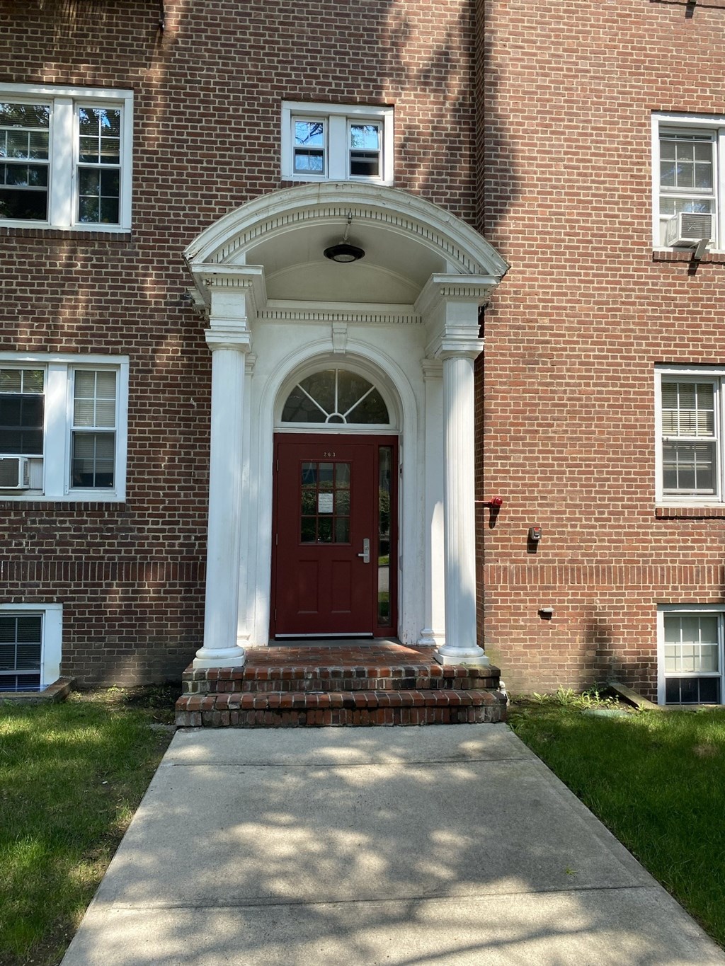 the front of a brick building with a red door and a porch