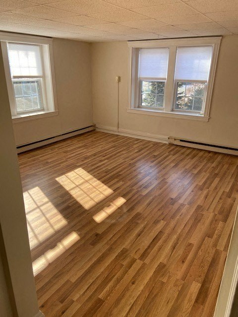 an empty living room with a wooden floor and three windows