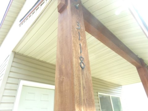 a close up of a porch post with a house in the background