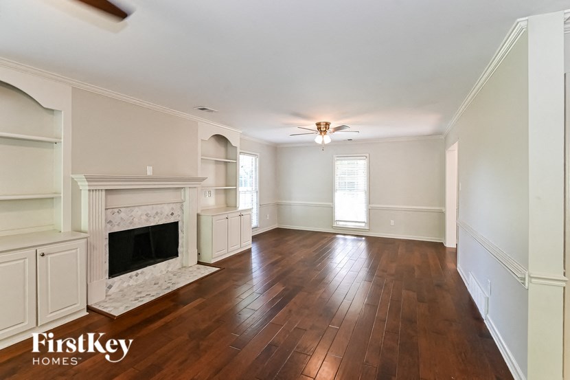 an empty living room with a fireplace and wooden floors