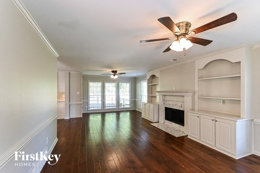 an empty living room with a ceiling fan and a fireplace