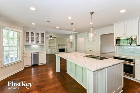 a large kitchen with white cabinets and a marble counter top