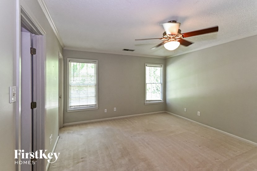 an empty living room with a ceiling fan and a window