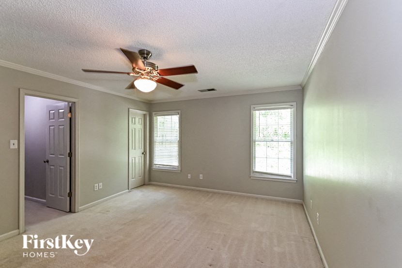 an empty living room with a ceiling fan and a door