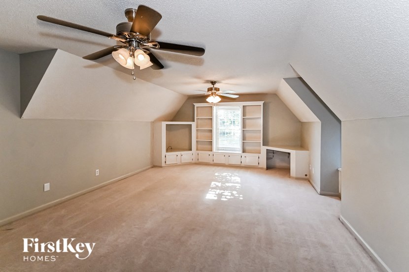 an empty living room with a ceiling fan and a closet