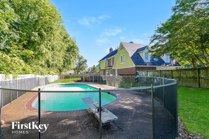 a backyard with a pool and a fence and a house