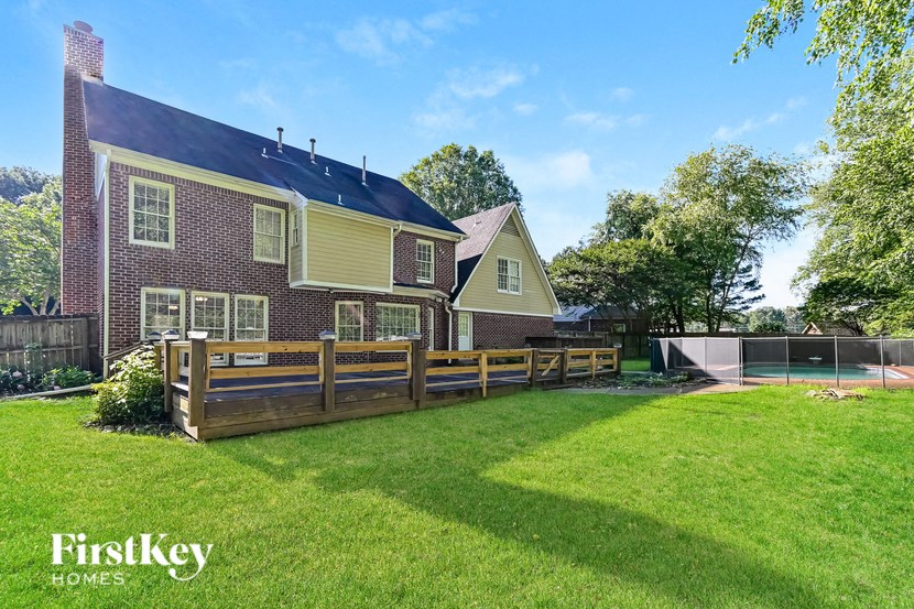 a backyard with a fence and a house with a tennis court