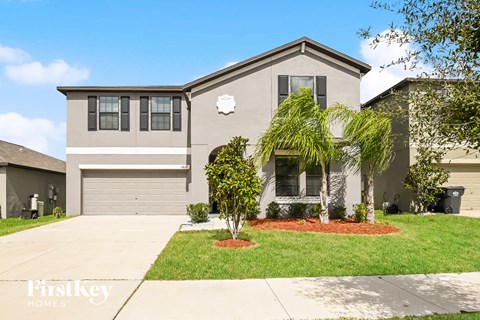 a beige house with a lawn and palm trees