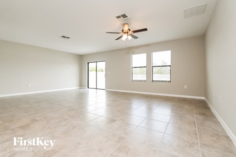 the spacious living room with tile flooring and a ceiling fan