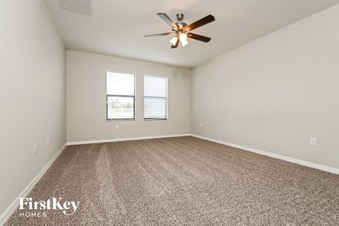 a spacious living room with carpet and a ceiling fan